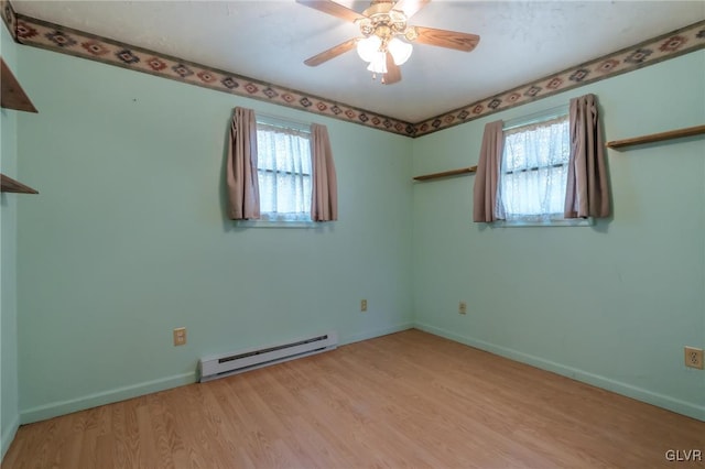 spare room with a baseboard radiator, baseboards, light wood finished floors, and a wealth of natural light