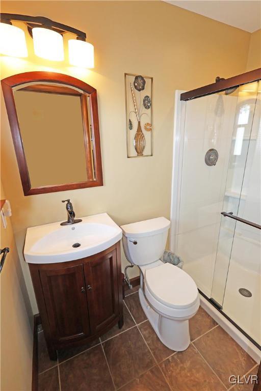 bathroom with tile patterned flooring, toilet, a shower stall, and vanity