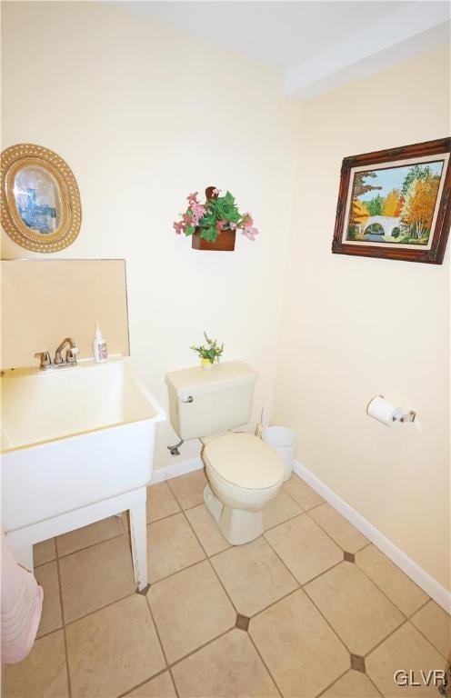 half bathroom featuring tile patterned flooring, baseboards, and toilet