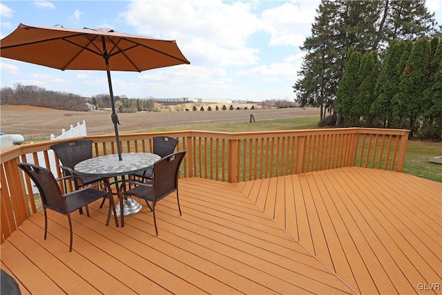 wooden deck with outdoor dining area and a rural view
