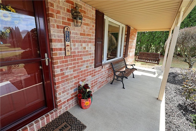 doorway to property with brick siding and covered porch
