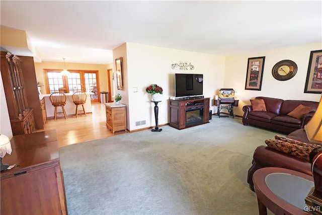 living room with visible vents, baseboards, a fireplace, french doors, and light colored carpet