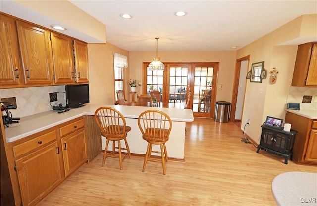 kitchen featuring brown cabinets, light countertops, light wood-style flooring, and a peninsula