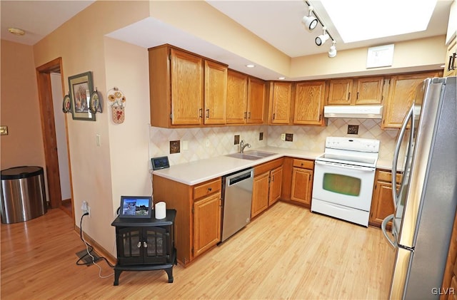 kitchen with light wood-type flooring, light countertops, under cabinet range hood, appliances with stainless steel finishes, and a sink