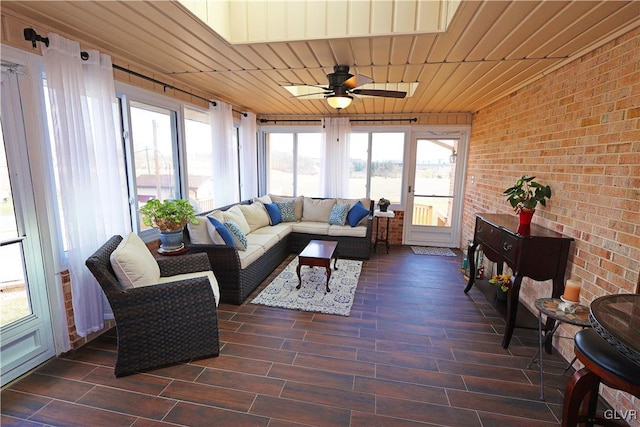 sunroom with brick wall, an outdoor living space, a ceiling fan, and wood finished floors