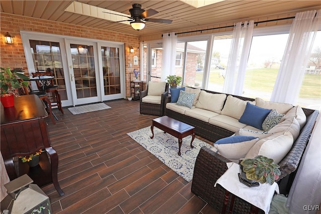 sunroom featuring french doors, brick wall, and ceiling fan