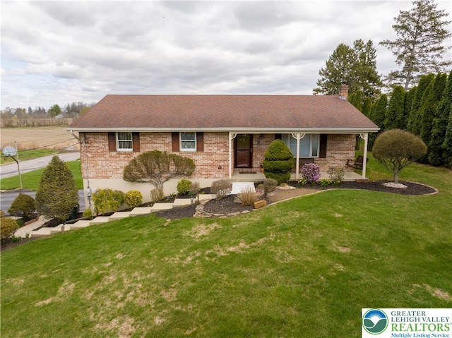 ranch-style house with a chimney, a front lawn, and brick siding
