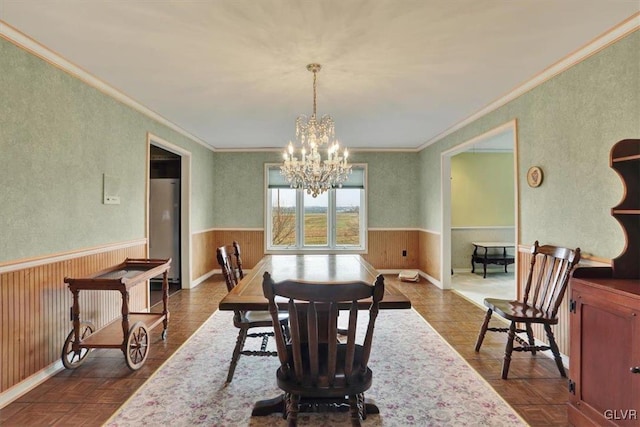 dining space featuring wooden walls, a wainscoted wall, and a chandelier