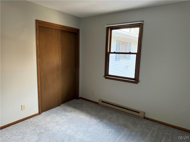 unfurnished bedroom featuring a closet, baseboards, carpet flooring, and a baseboard heating unit