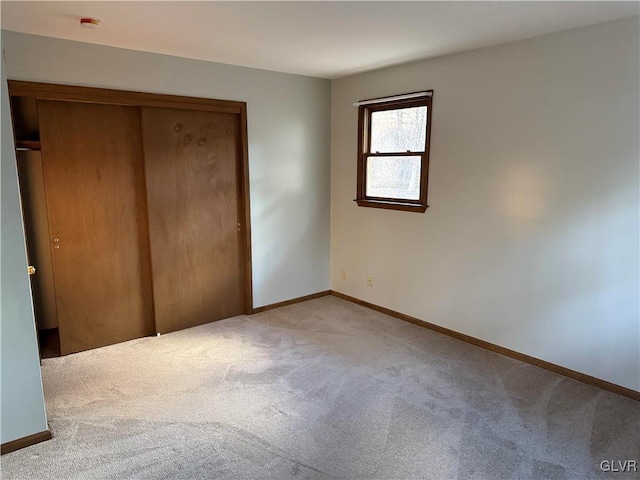 unfurnished bedroom with carpet, a closet, and baseboards