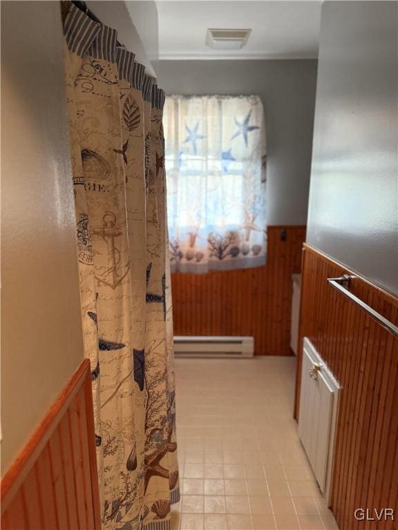 bathroom with visible vents, a baseboard radiator, wainscoting, and wood walls