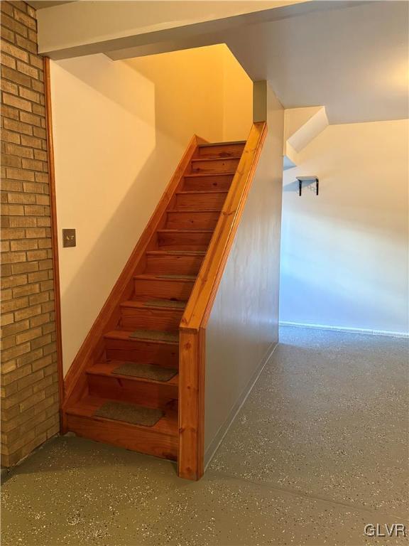 staircase with brick wall and speckled floor