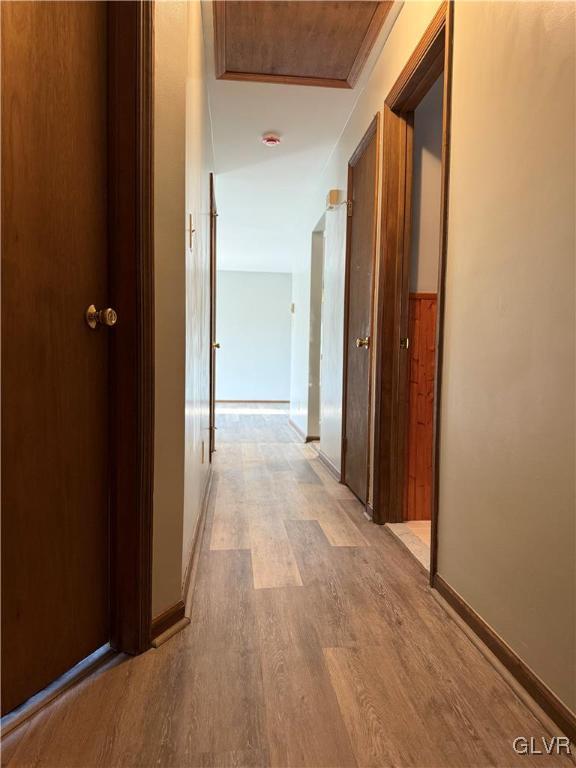 corridor featuring light wood-style flooring and baseboards