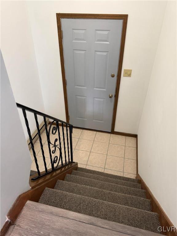 staircase featuring baseboards and tile patterned flooring