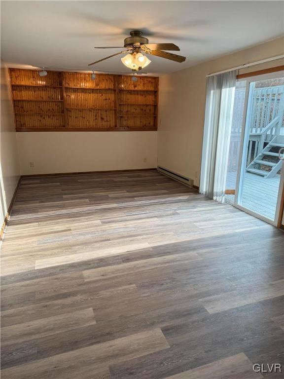unfurnished room with ceiling fan, a baseboard heating unit, and wood finished floors