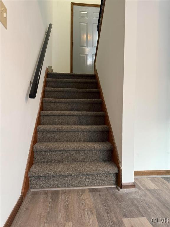 staircase featuring baseboards and wood finished floors