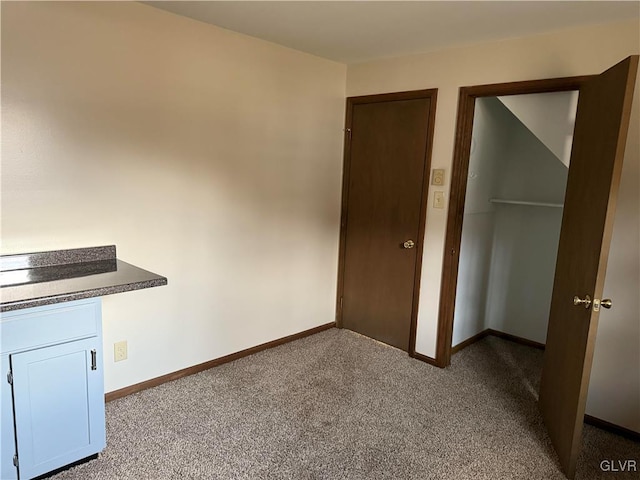 unfurnished bedroom featuring dark carpet and baseboards