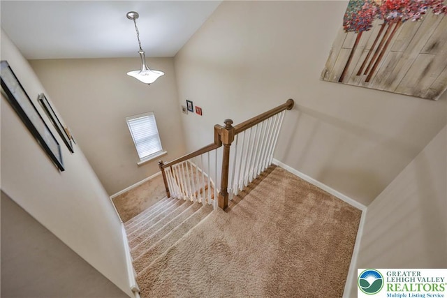 staircase featuring baseboards, lofted ceiling, and carpet