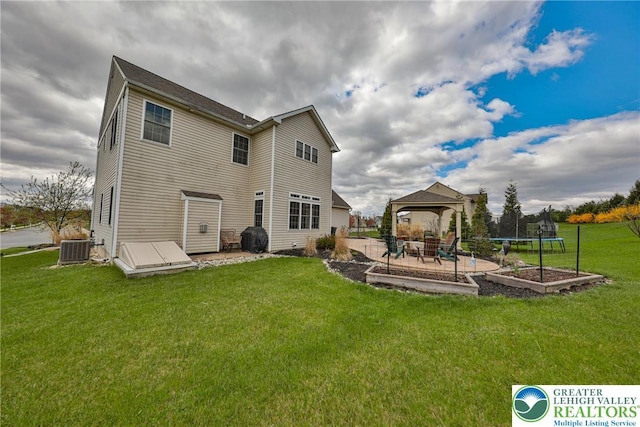 rear view of house with a trampoline, a patio, a yard, central AC, and a gazebo