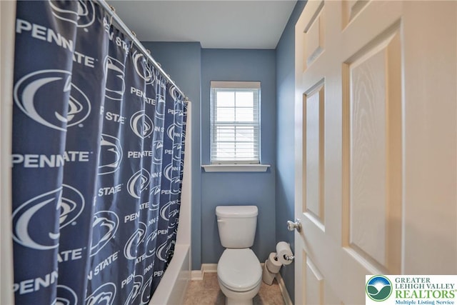 bathroom with tile patterned floors, shower / bathtub combination with curtain, baseboards, and toilet