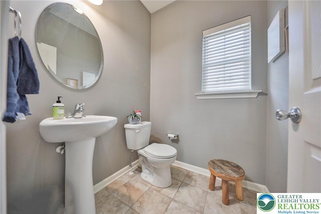 bathroom with baseboards, a sink, and toilet