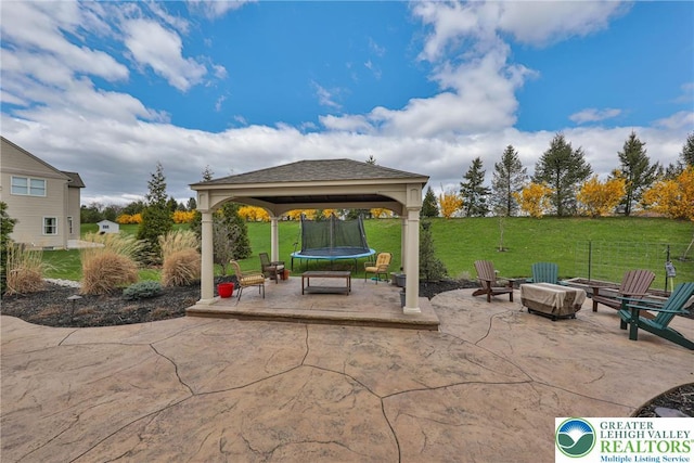 view of patio featuring a trampoline, a gazebo, and an outdoor fire pit