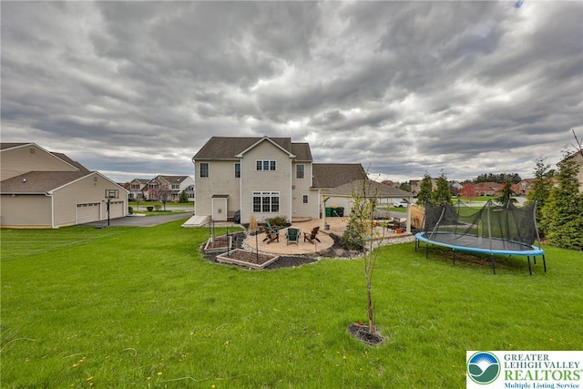 back of property featuring a trampoline, a residential view, a patio area, a garage, and a yard
