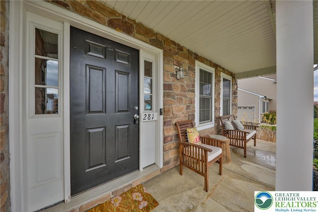 view of exterior entry featuring a porch and stone siding