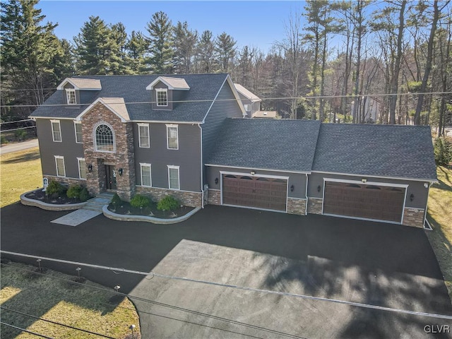 view of front of house featuring roof with shingles, stone siding, a garage, and aphalt driveway