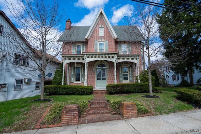 221 Franklin St, Alburtis Borough, PA 18011 - view of front of house with a porch, a wall mounted AC, a chimney, brick siding, and a front lawn