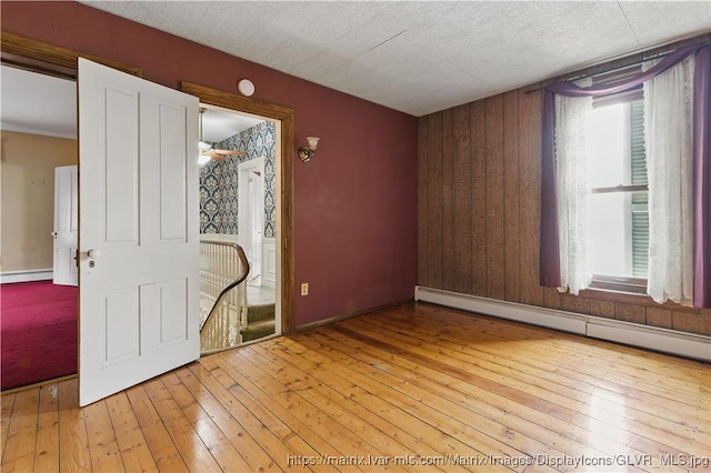 221 Franklin St, Alburtis Borough, PA 18011 - empty room with baseboards, a baseboard heating unit, wooden walls, hardwood / wood-style floors, and a baseboard radiator