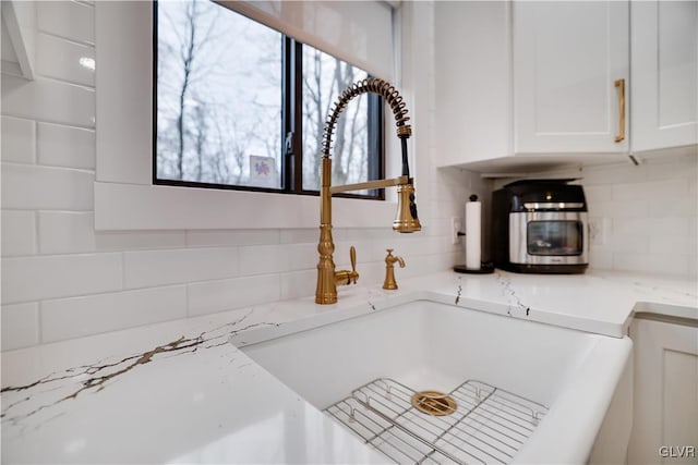 5627 Pembrook Dr, Coolbaugh Twp, PA 18466 - kitchen view of tasteful backsplash, white cabinets, and light stone countertops