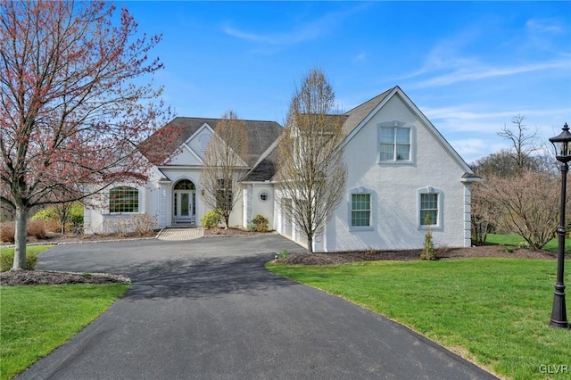 view of front facade featuring french doors, a front lawn, driveway, and stucco siding
