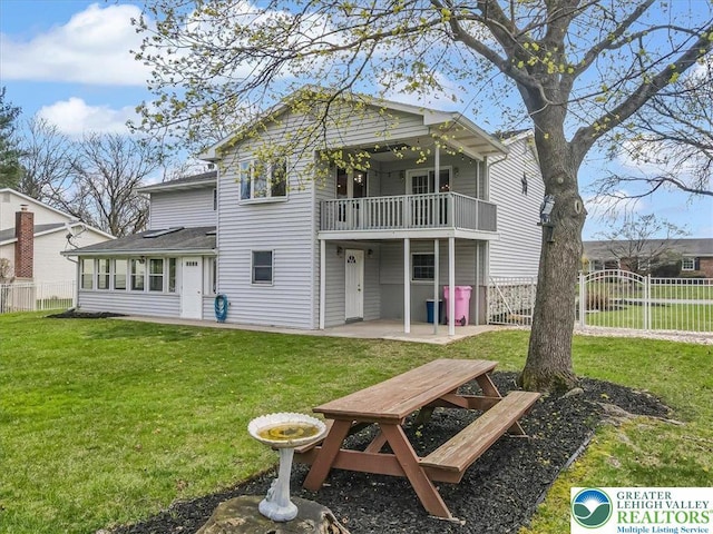 rear view of property featuring a yard, fence, and a patio