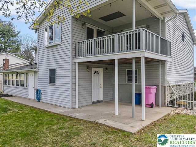 rear view of house with a patio area, a yard, and a balcony