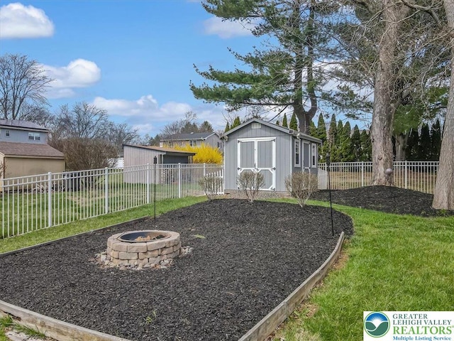 view of yard with a fenced backyard, an outdoor structure, a fire pit, and a storage unit