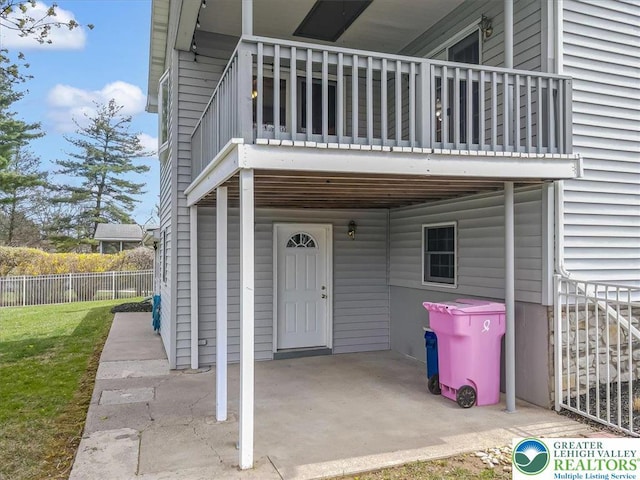 property entrance featuring a yard, fence, and a balcony