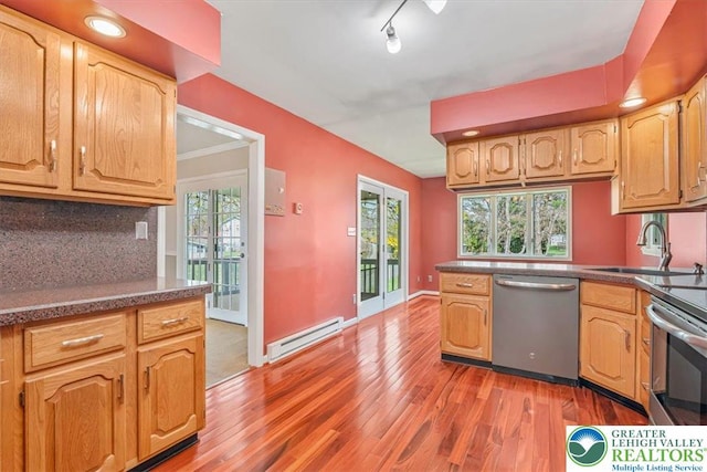 kitchen featuring light wood-type flooring, appliances with stainless steel finishes, a sink, a baseboard radiator, and decorative backsplash