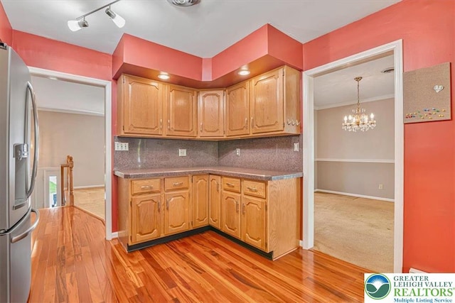 kitchen featuring stainless steel fridge with ice dispenser, backsplash, light wood finished floors, and an inviting chandelier