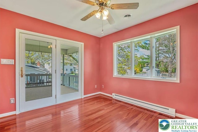 unfurnished room featuring ceiling fan, visible vents, baseboard heating, wood finished floors, and baseboards