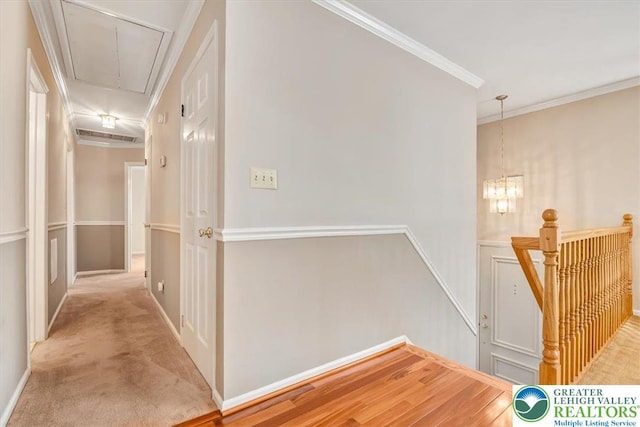 hall featuring carpet, ornamental molding, attic access, an upstairs landing, and baseboards