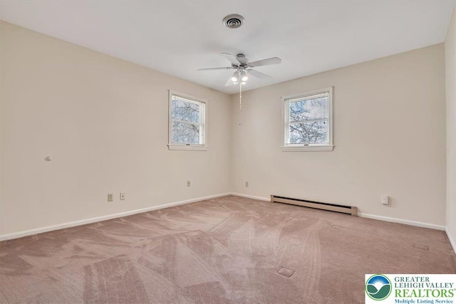 empty room with a healthy amount of sunlight, a baseboard heating unit, ceiling fan, and visible vents