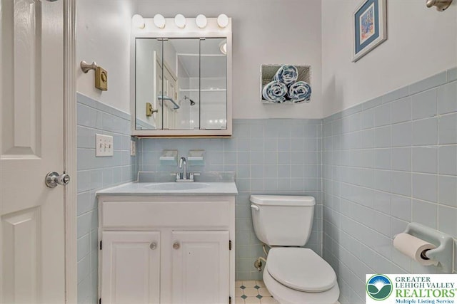 bathroom with vanity, tile walls, a wainscoted wall, and toilet