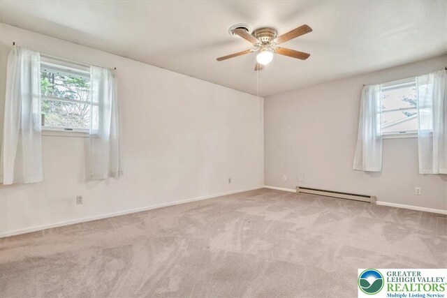carpeted empty room featuring baseboard heating, baseboards, and a ceiling fan