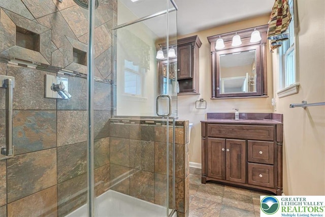 full bathroom with a shower stall, a healthy amount of sunlight, vanity, and stone finish floor