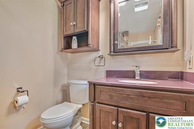 bathroom with toilet, vanity, and baseboards