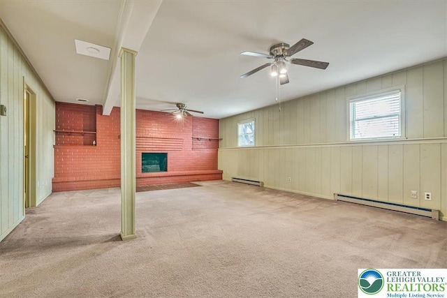 unfurnished living room with a baseboard heating unit, brick wall, a brick fireplace, ceiling fan, and carpet