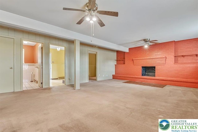 unfurnished living room featuring a ceiling fan, light colored carpet, and a brick fireplace