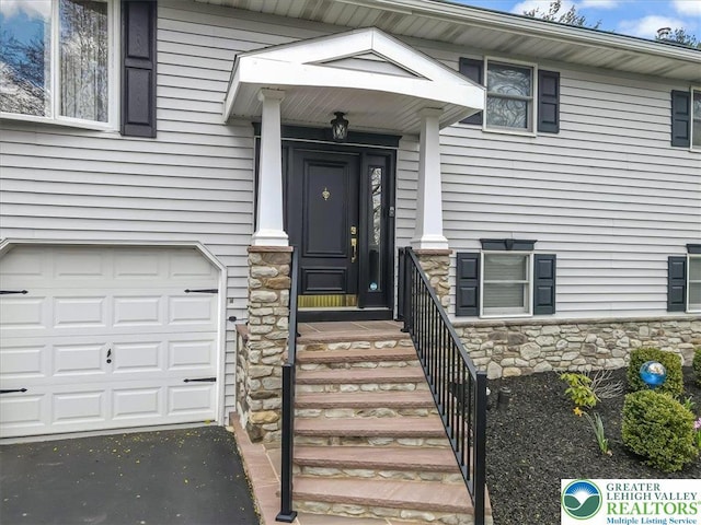 entrance to property with an attached garage and stone siding