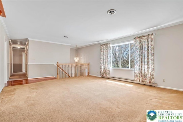 carpeted empty room featuring crown molding, visible vents, attic access, and a baseboard heating unit